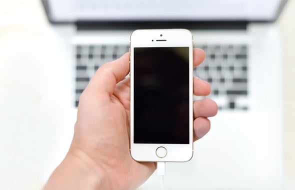 Person holding an iPhone in front of a MacBook